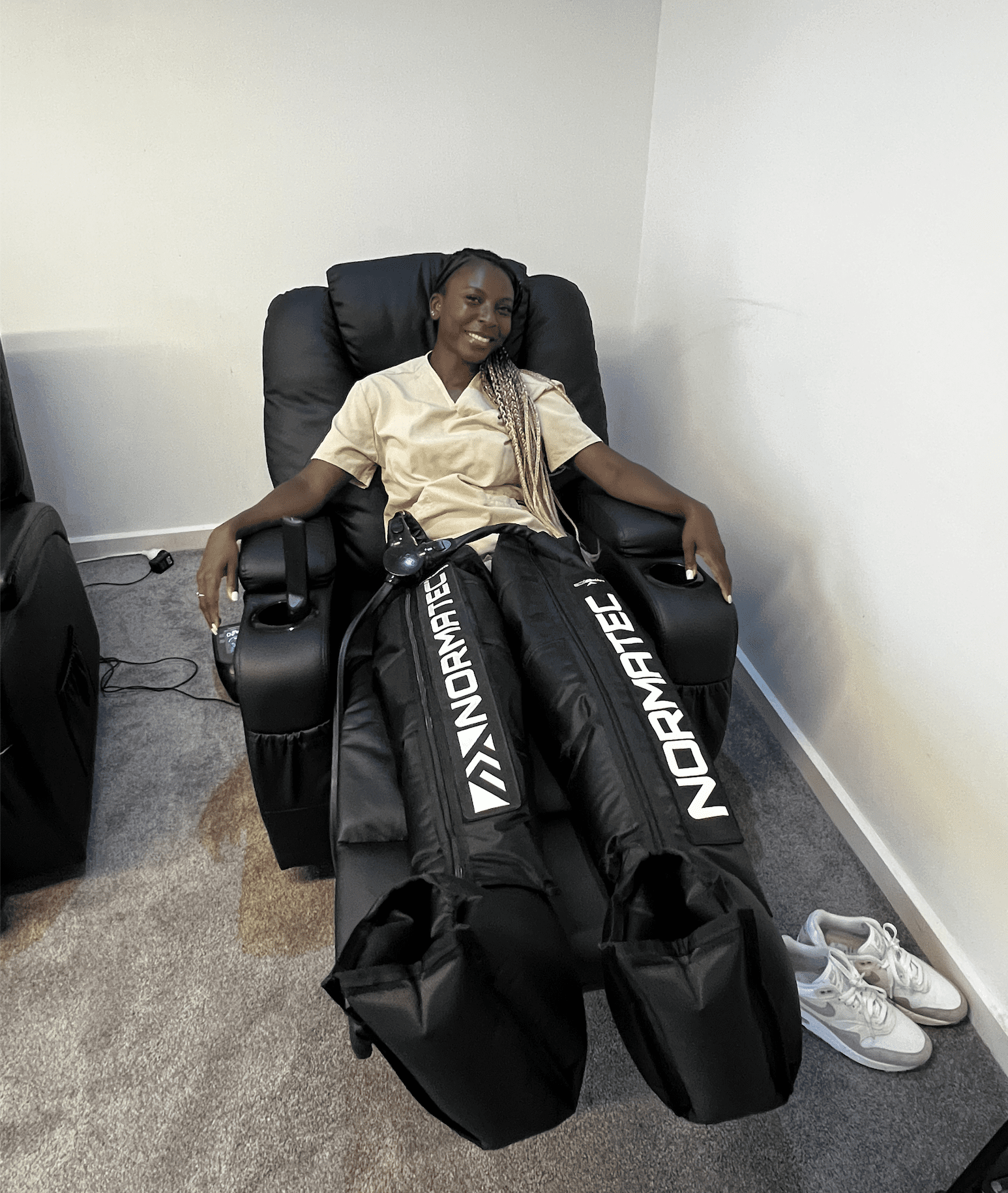 Veronica, a registered nurse, comfortably seated in Normatec pants, promoting relaxation and recovery at Fresh Treatment.