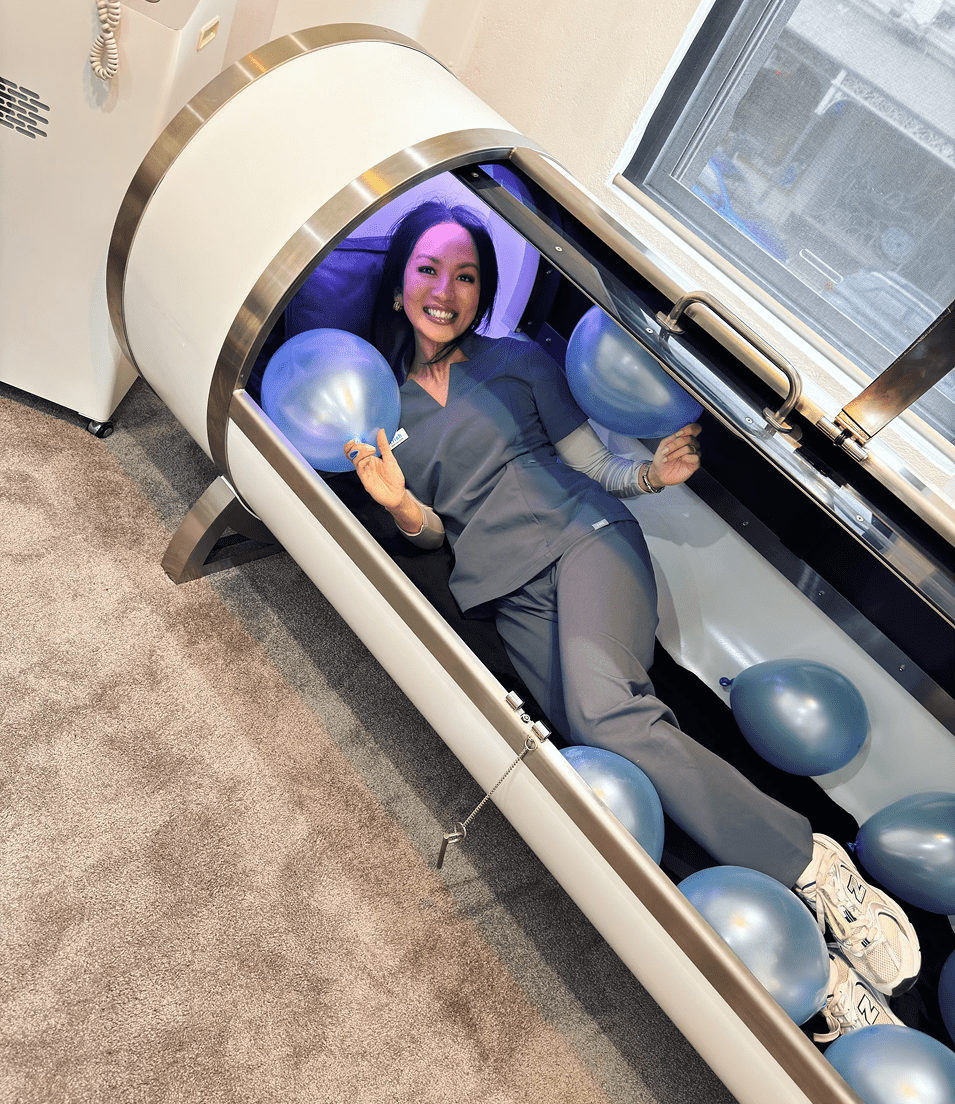 Trish, a registered nurse, confidently posing inside the chamber, ready to assist with wellness treatments at Fresh Treatment.