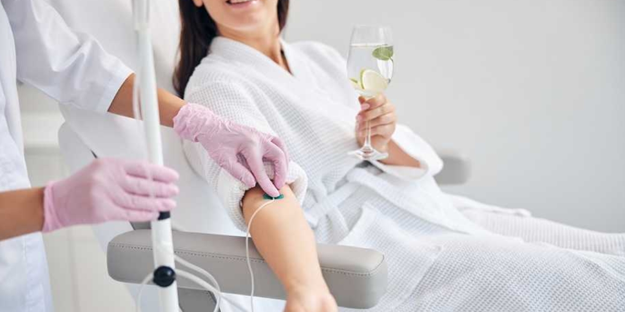 a patient holding a glass while getting an IV drip